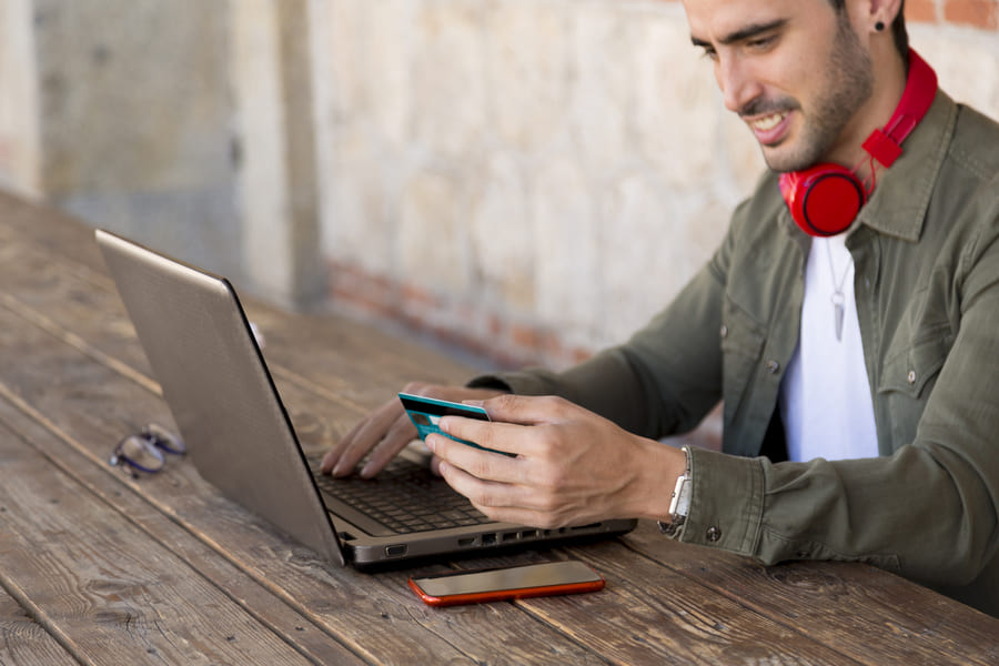 homem fazendo compra online no seu notebook com seu cartão de crédito